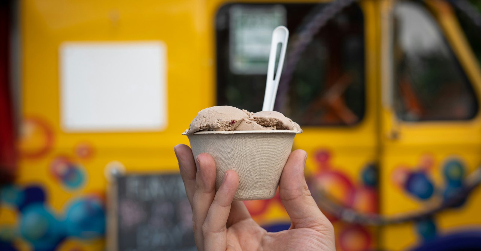 A customer holding a tub of ice cream in front of a food truck