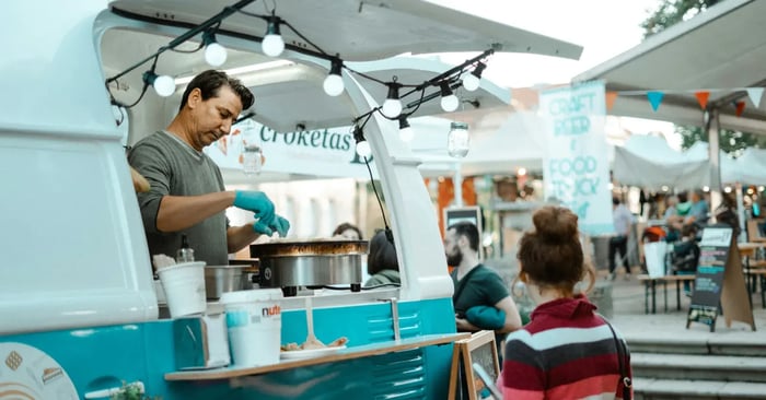Customers queuing at food trucks in an outdoor market